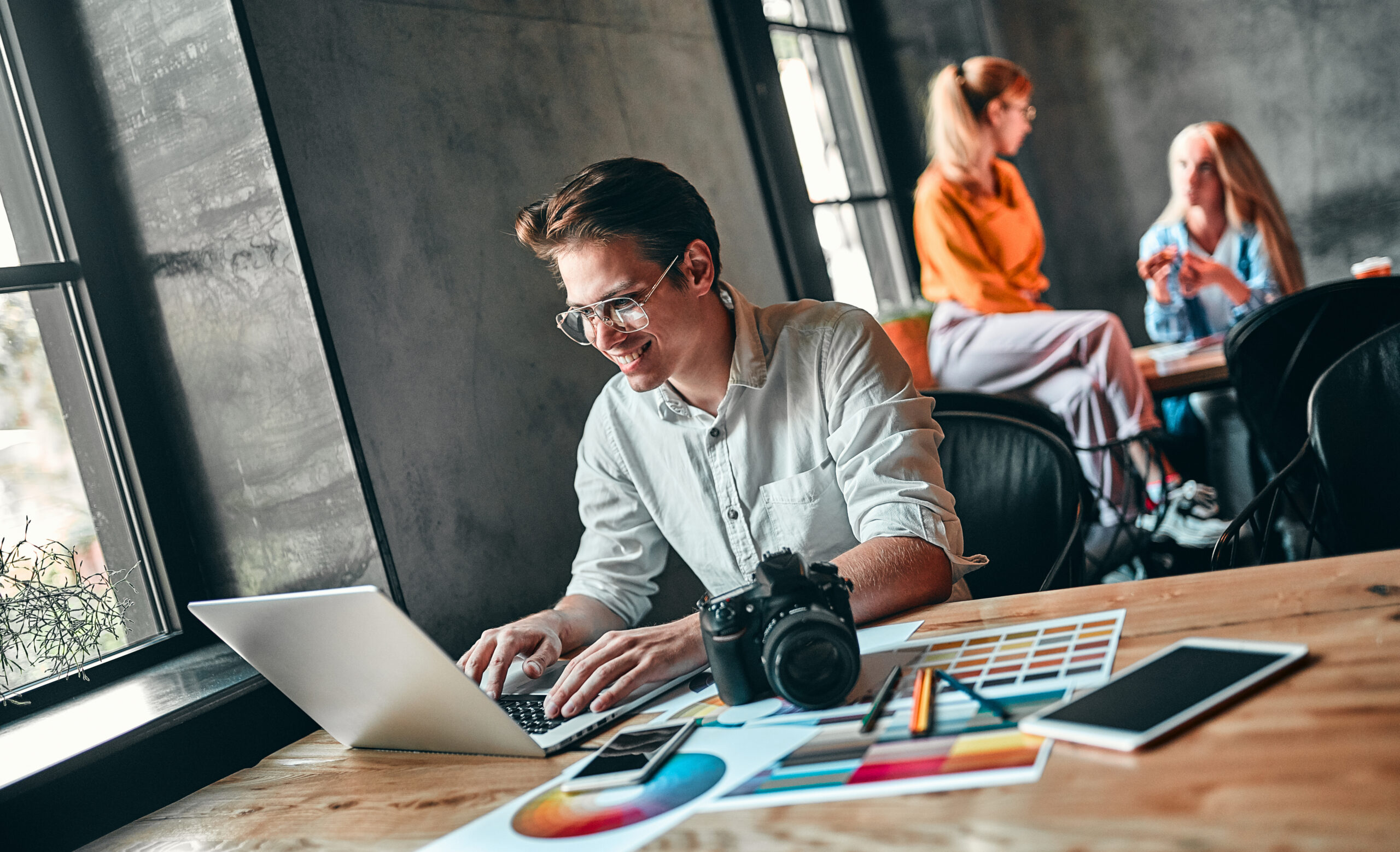 Generating new ideas. Young photographer looking at laptop while sitting at his working place.